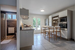 A modern kitchen with a central island, built-in appliances, and a dining area with bar stools.