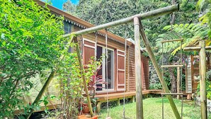Uma cabana de madeira com baloiço e escada de corda.