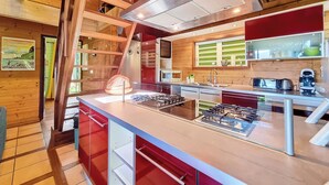 Cozinha moderna com ilha central, eletrodomésticos de aço inoxidável e vigas de madeira.