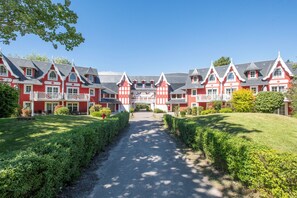 A large red and white building with a symmetrical facade, a central entrance, and a paved pathway leading to it. - Belle Dune - Balcon - Plage (Fort-Mahon-Plage)