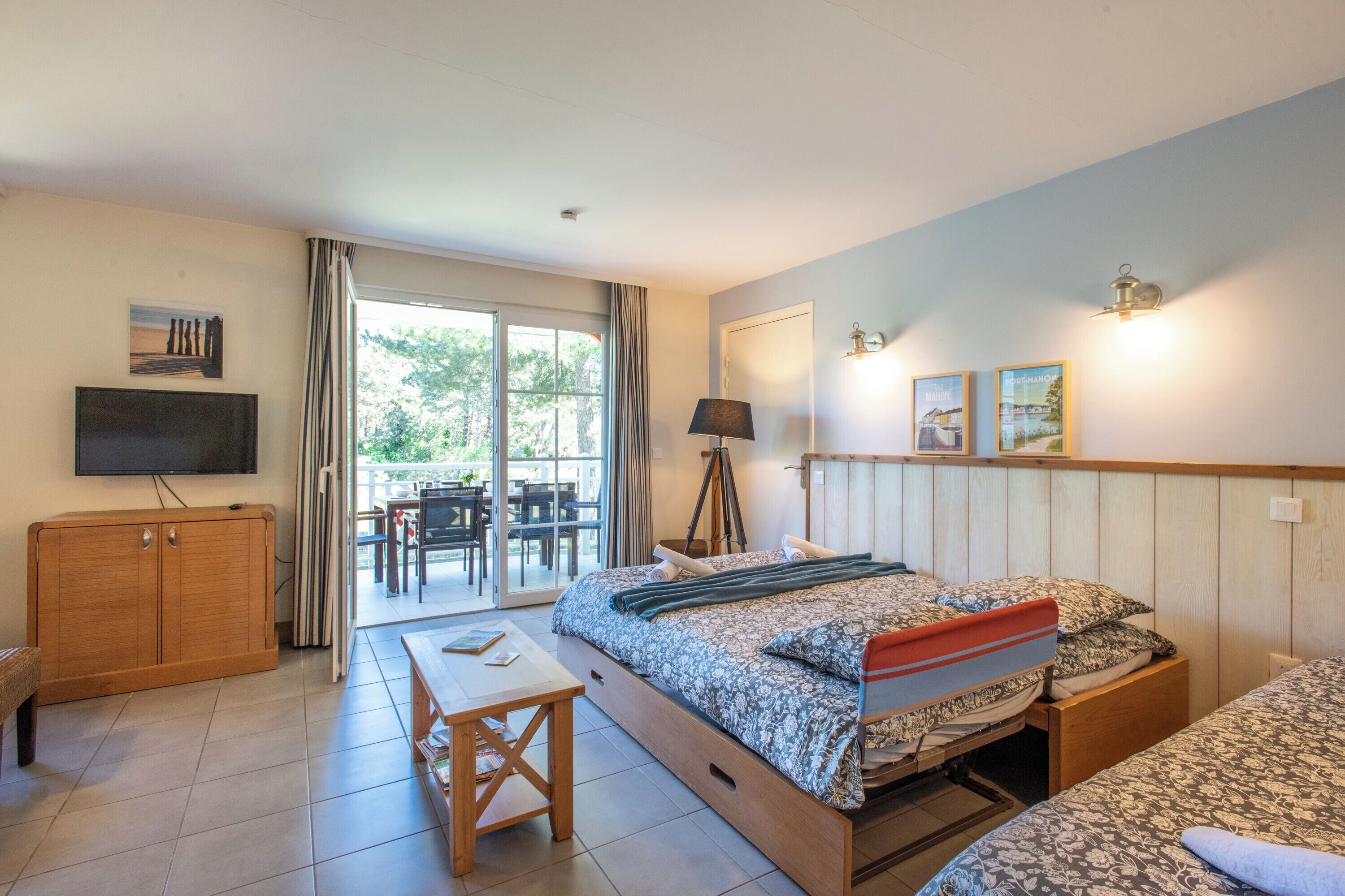 Une chambre avec un lit, un bureau, une télévision et une porte coulissante donnant sur un espace extérieur.