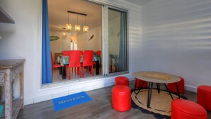 Ein modernes Zimmer mit einer Schiebetür zu einem Essbereich, einem kleinen runden Tisch mit Teppich und zwei roten Hocker.