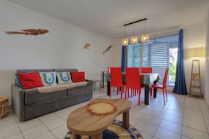 A living room with a sofa, a coffee table, red chairs, a dining table, and a ceiling fan. - Ti paradis - Climatisation - Wifi (Saint-Paul)