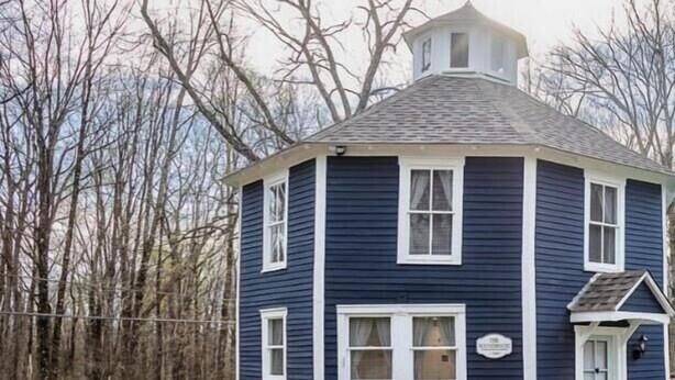 A two-story house with a gabled roof, a front porch, and a small garden area. - Cozy 3BR Octagon Cabin-Near Ricketts Glen (Benton)