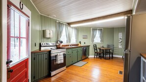 A kitchen with green cabinets, a wooden countertop, a stove, a sink, and a refrigerator. - Cozy 3BR Octagon Cabin-Near Ricketts Glen (Benton)