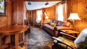A wooden interior with a leather sofa, a dining table, and a lamp. - Cozy 3BR Octagon Cabin-Near Ricketts Glen (Benton)