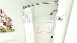 Un baño con ducha, un armario con cajones y una puerta.