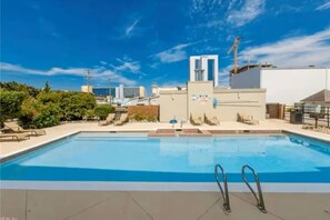 A rooftop swimming pool with a clear blue sky, surrounded by buildings and greenery. - Playa Sin Olas - Virginia Beach - Walk To Beach - Family Friendly (Virginia Beach)