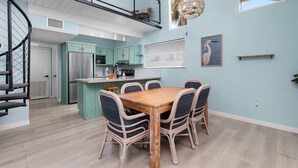 Una cocina moderna con comedor, una escalera y vistas al exterior.