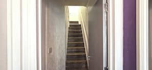 A narrow hallway with a wooden staircase leading to a landing. - Apartment Sleeps 4 With Wifi (Clacton-on-Sea)
