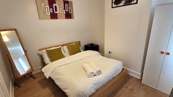 Quarto com cama, mesa de cabeceira, guarda-roupa e espelho.