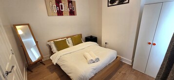 A bedroom with a bed, a nightstand, a wardrobe, and a mirror.