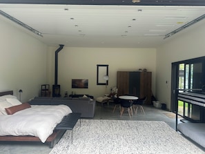 A modern bedroom with a bed, a sofa, a dining table, and a TV.