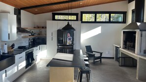 A modern kitchen with a central island, built-in appliances, and a large window. - Modern-Japanese Inspired - Indoor/Outdoor Luxury Rental (Riondel)