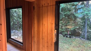 A wooden interior with a large window and a door leading outside. - Modern-Japanese Inspired - Indoor/Outdoor Luxury Rental (Riondel)