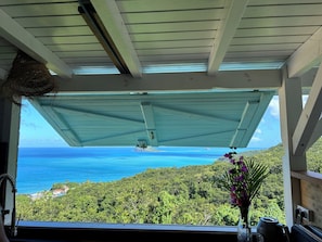 Una stanza con vista sull'oceano, un nido sospeso e un vaso con fiori.