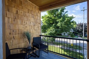 Ein Holzbalkon mit Blick auf eine Straße und Bäume.