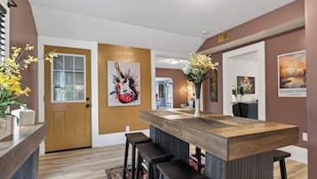 Una cocina moderna con una isla de madera, taburetes de bar y detalles decorativos como flores y obras de arte.