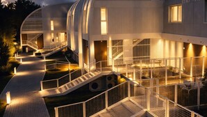 Ein modernes Gebäude mit geschwungener Außenfassade, mehreren Ebenen und einem zentralen Innenhof mit einer Treppe.