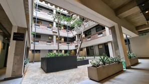 A multi-level atrium with a central staircase, potted plants, and a tiled floor.