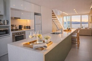 Una cocina moderna con una isla central, electrodomésticos de acero inoxidable y vistas al exterior.