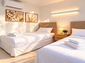 Ein Hotelzimmer mit zwei Betten, einem Nachttisch mit Lampe und Wandaircondition.