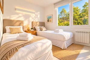 A hotel room with two beds, a bedside table with a lamp, a view of trees through the window, and a radiator. - Signature Lake View Luxury Residences Unit H25 (BARILOCHE - SAN CARLOS DE BARILOCHE)