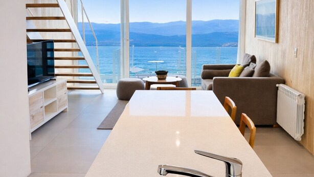 Una cucina moderna con una grande isola, un lavello integrato e vista sul mare.