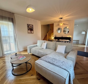 A living room with a sofa, a coffee table, and a dining area with a table and chairs. - Villa Desbrulys - Maison de ville pour 6 personnes - Terrasse - Climatisée (Brive-la-Gaillarde)