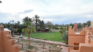 Un patio con palmeras, una zona de estar techada y arquitectura tradicional.