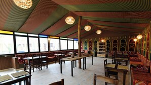Un restaurante con paredes estampadas, muebles de madera y lámparas colgantes.