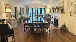 Un comedor con una gran mesa de madera, sillas, un piano y una chimenea.