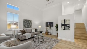 Ein geräumiges Wohnzimmer mit einer Couch, Sesseln, einem Couchtisch und Kunstwerken an den Wänden.
