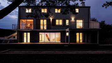 Une maison moderne à deux étages, dotée de grandes fenêtres, d’un balcon et d’un escalier.