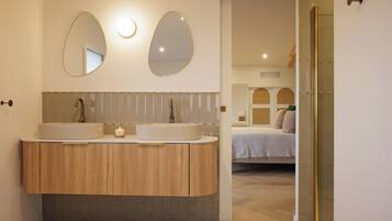 Une salle de bain moderne avec deux lavabos, un miroir et un espace douche.