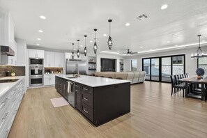 A modern kitchen with white cabinets, a central island, and pendant lighting. - Modern 7-bed Luxury retreat in Hurricane (Hurricane)