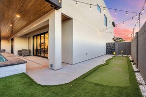Une maison moderne dotée d’un patio, d’une piscine et d’une pelouse bien entretenue.