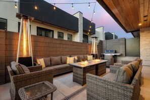 Une terrasse extérieure aménagée avec des meubles en osier, un foyer et un espace barbecue.