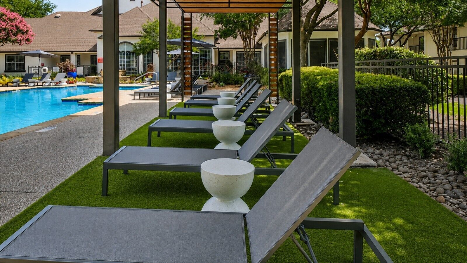 A poolside area with lounge chairs and a pergola.