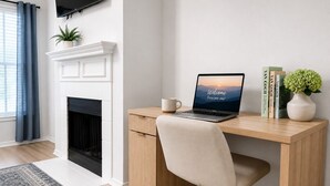 Un espacio de oficina moderno con un escritorio, una silla, una computadora portátil y una chimenea.