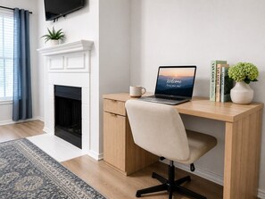 Ein moderner Büroraum mit Schreibtisch, Stuhl, Laptop und Kamin.