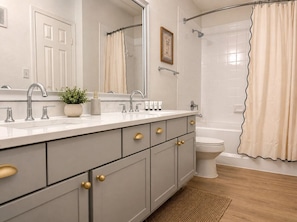 Ein Badezimmer mit Waschbecken, Spiegel, Schrank, Toilette und Duschvorhang.