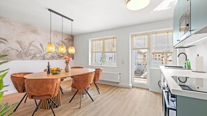 A modern kitchen with a dining area, large windows, and a view of the city. - Svyvo Bonn - City Apartments (Bonn)