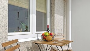 A wooden table with a fruit bowl and wine glasses, a bench, and a window with blinds. - Svyvo Bonn - City Apartments (Bonn)