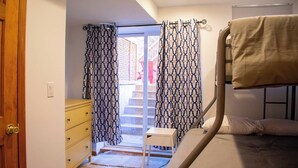 Ein Schlafzimmer mit Etagenbett, Holztür, gelbem Schminktisch und gemusterten Vorhängen.
