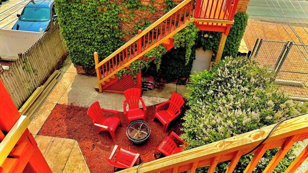 Eine Dachterrasse mit einer Holztreppe, roten Stühlen und einer Feuerstelle.