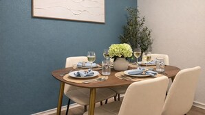 Un coin repas avec une table ronde, des chaises, un vase de fleurs et un tableau accroché au mur.