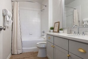 Un baño con bañera, inodoro y tocador con espejo.
