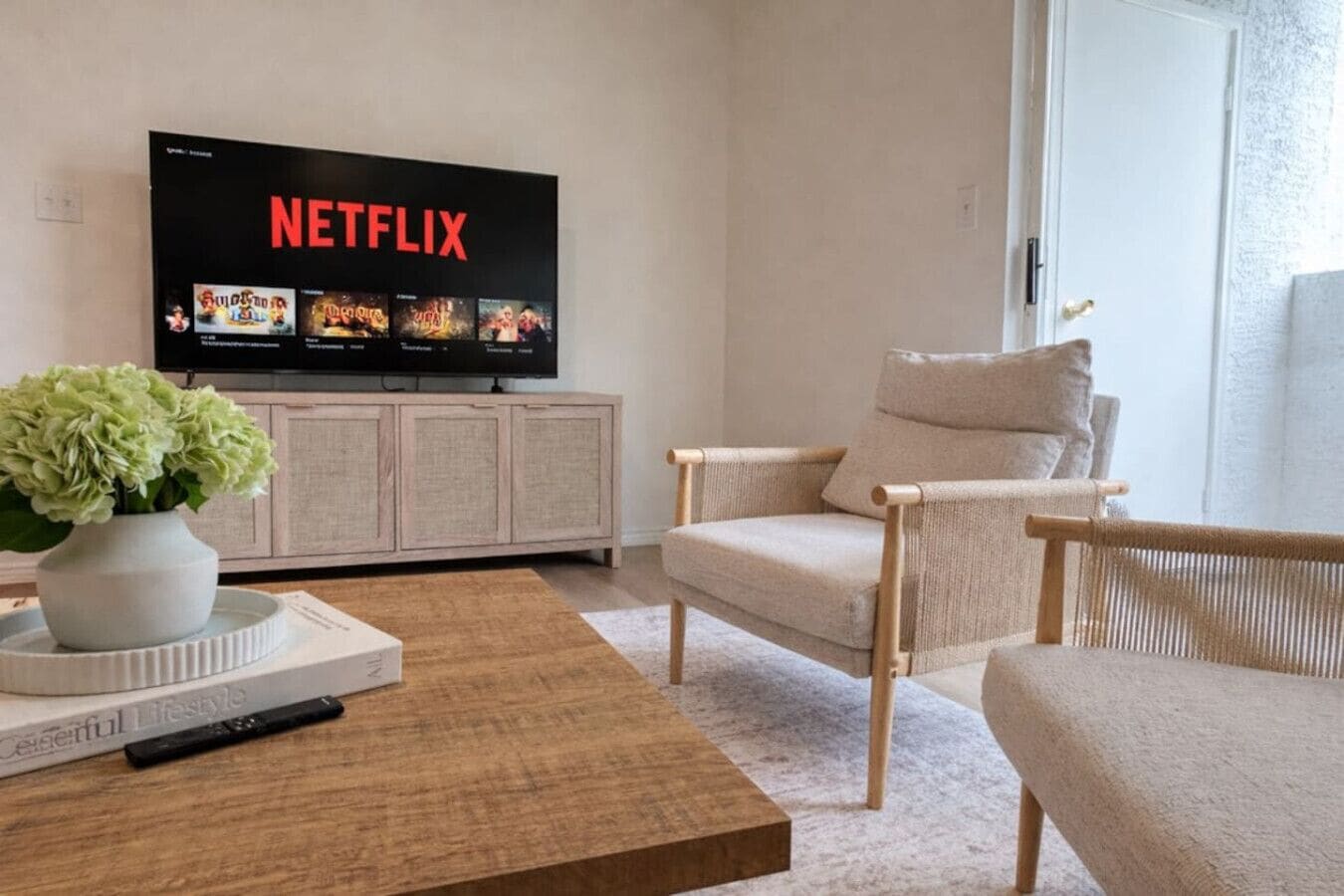 A living room with a television displaying Netflix, a sofa, a coffee table, and a bookshelf.