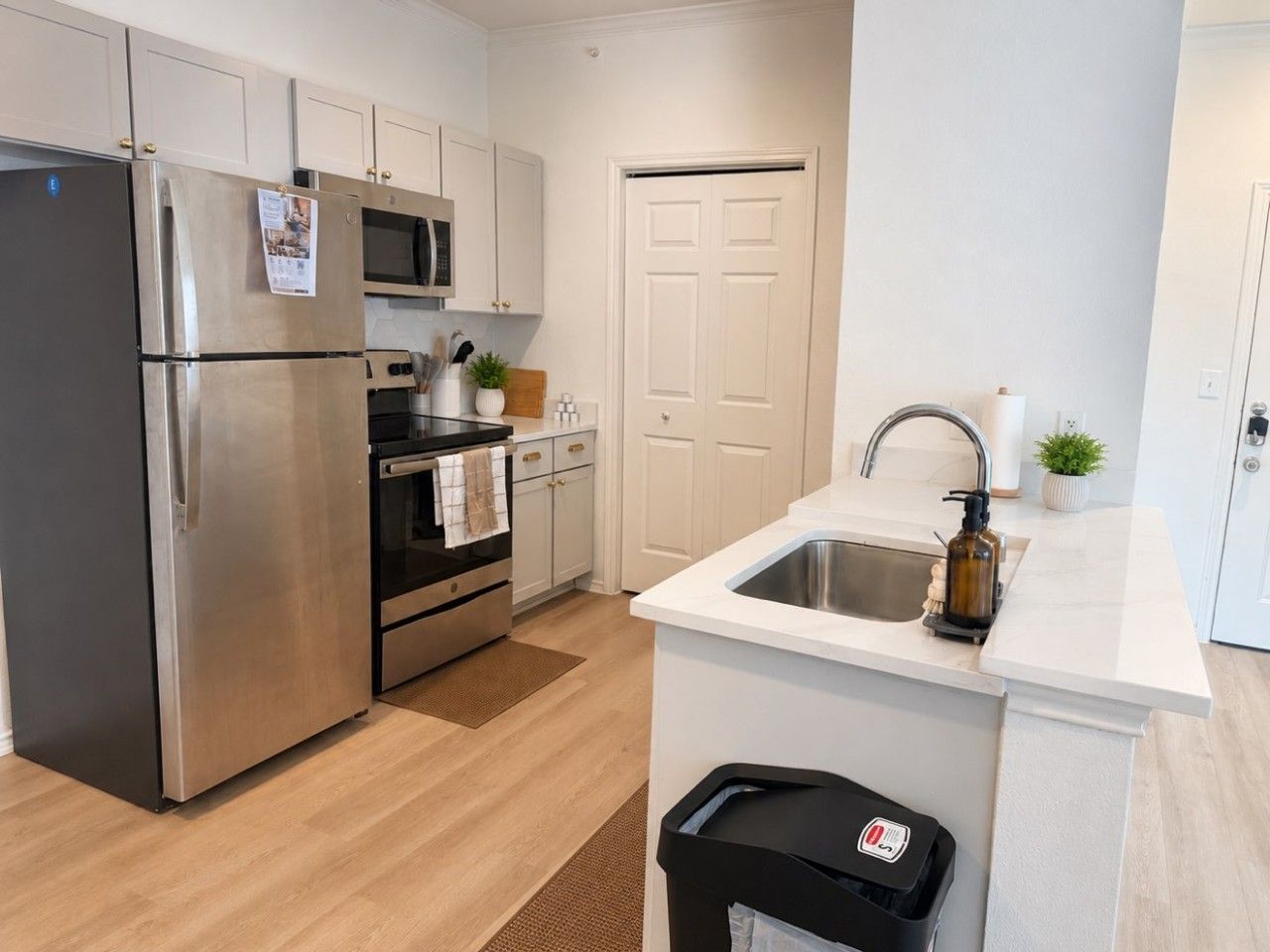 A modern kitchen with stainless steel appliances, a built-in oven, a microwave, and a sink with a soap dispenser.